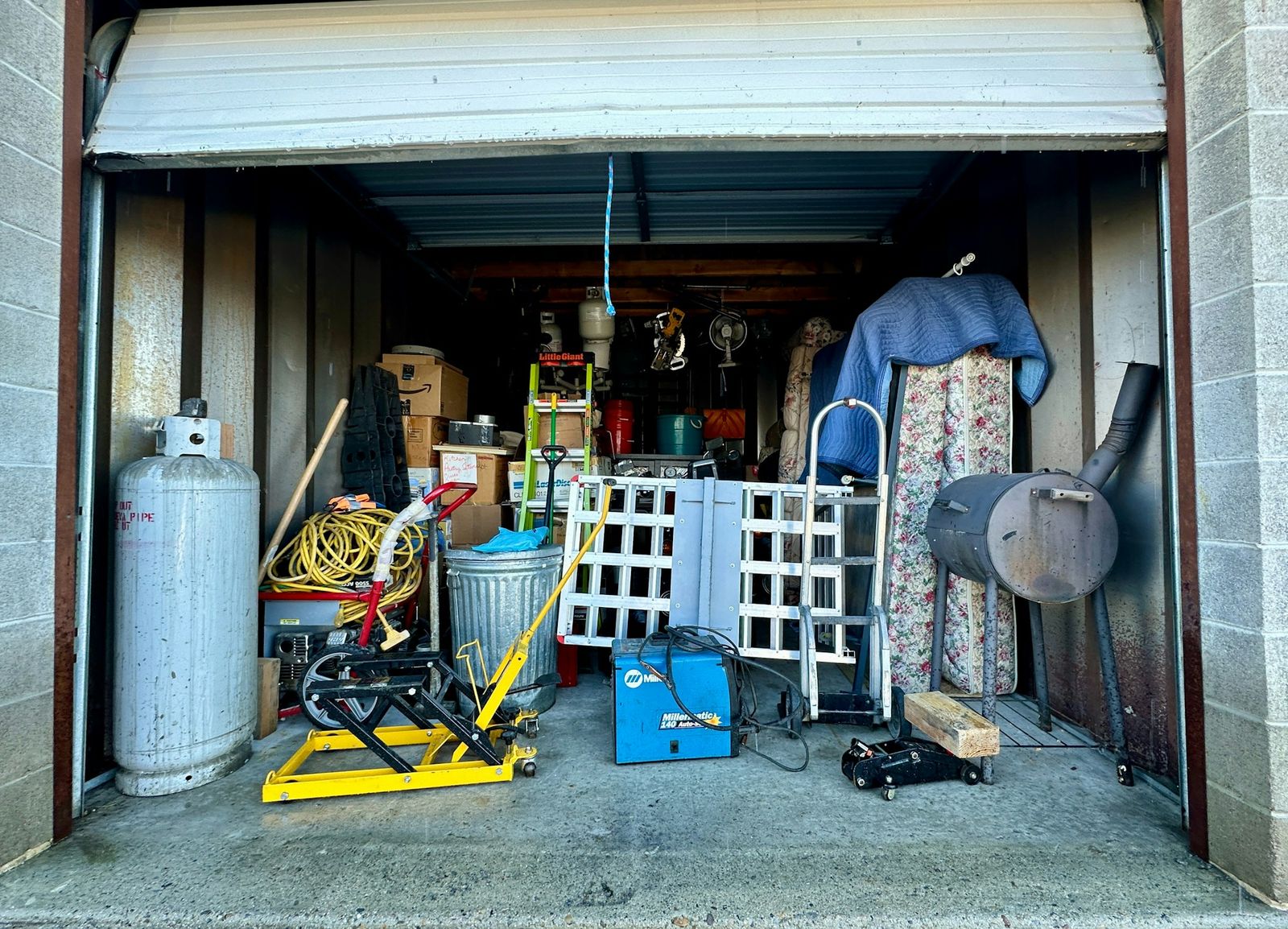 A storage unit packed with old furniture, tools and clutter ready to be cleared out